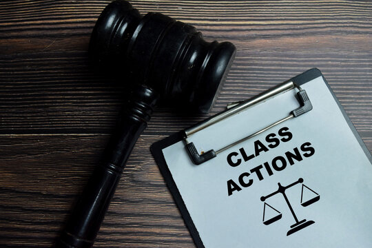 Concept of class actions write on clipboard isolated on Wooden Table. Representing legal compliance and litigation exposure assessment