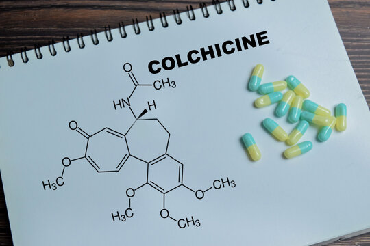 Concept of colchicine anti inflammatory therapy write on book isolated on Wooden Table. Treatment of gout and chronic inflammation