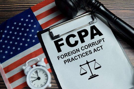 Concept of FCPA - Foreign Corrupt Practices Act write on clipboard isolated on Wooden Table. For corporate ethics, anti bribery controls and internal audit