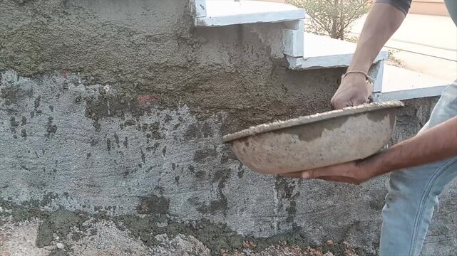 Man applying concrete to wall with trowel and bucket
