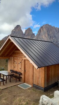 Wooden mountain cabin in alpine landscape with dramatic peaks of the Dolomites, peaceful nature retreat and sustainable travel concept.