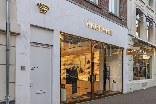 Versace luxury boutique storefront. Elegant marble facade with gold logo and Medusa emblem on a busy city street. Amsterdam Netherlands, 28 december 2025