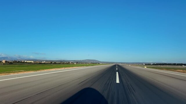 An immersive pilot&rsquo;s eye view from the cockpit of an airplane exiiting the runway, with the shadow of the nose of the plane on the runway. Sunny day with a blue sky. Palma Airport (PMI).