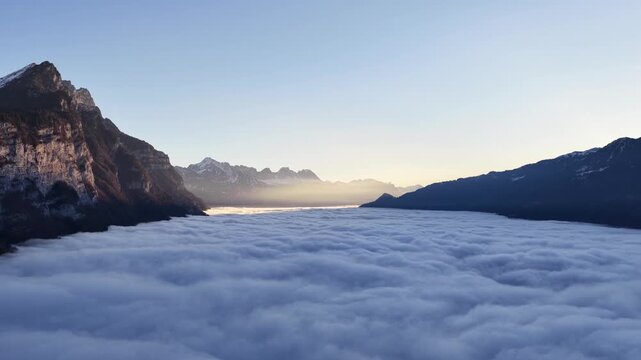 Churfirsten mountains near Walensee Switzerland covered by thick cloud sea, drone view of calm morning peaceful alpine atmosphere.