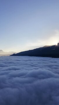 Churfirsten mountains Switzerland with soft sunrise light above dense cloud sea as vertical drone rises calm atmospheric alpine mood.