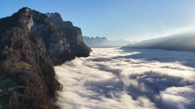 Churfirsten mountains near Walensee Switzerland covered by flowing cloud sea as drone view of alpine landscape and peaceful morning mood.