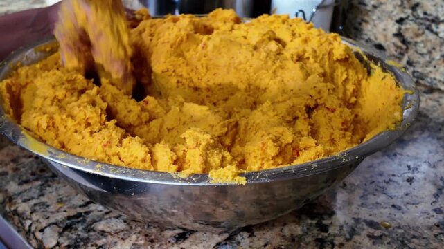 handmade process of kneading yellow corn flour dough in a metal bowl for traditional Latin American ethnic food preparation.