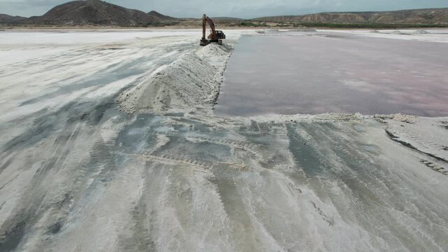 Aerial view of excavator working on white salt piles in Araya Salinas