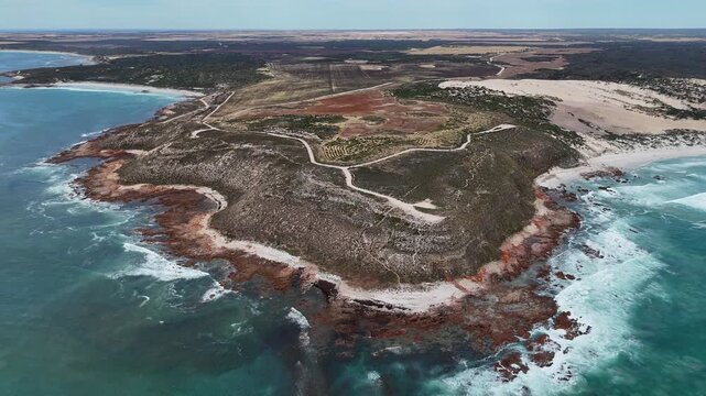 Aerial establishing medium of exposed rocky peninsula surrounded by blue ocean at Salmon Hole, Daly Head, pullback