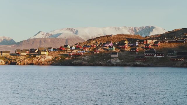 Camera flies toward Iqqortoormiit, Greenland just above the water slowly rising as it gets closer to totwn.