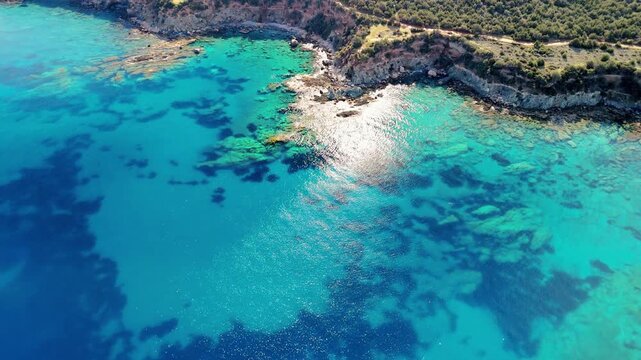 Top-down aerial view of rocky shoreline and turquoise sea in Cyprus. Textured coastal formations and clear water seen from above. Ideal for nature, geology and abstract drone footage.