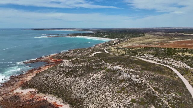 Aerial dolly of Daly Head headland with winding coastal road and expansive ocean, establishing background