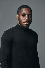 Obraz premium African man portrait in creative conceptual visual style wearing black turtleneck sweater with confident expression on gray background studio shot.