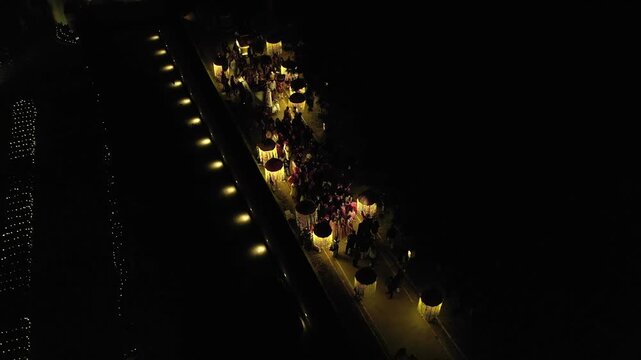Aerial night shot of a traditional Indian wedding baraat with decorated car, dancers, and festive lights in india