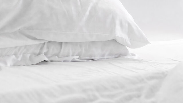 White bedding with stacked pillows on a soft mattress in a bright setting