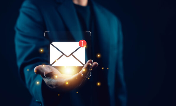 Businessman holding glowing email notification icon with new message alert, concept of digital communication, email marketing, customer support, online messaging, inbox management, business technology