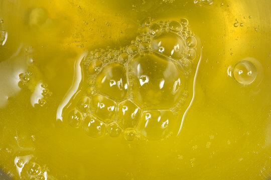 A detailed macro shot showing the viscous texture and clear surface of raw liquid egg whites with a cluster of air bubbles during food preparation