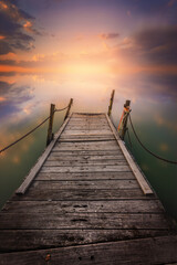 Fototapeta premium Rustic Pier on a Calm Lake with a Dramatic Sunset Sky