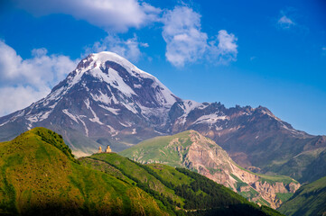 view of Gergeti trinity church or Tsminda Sameba with background of mountains landscape, Stepantsminda, Kazbegi city, Georgia.
