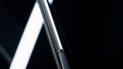 Close-up of a sleek metal hinge on a dark background.
