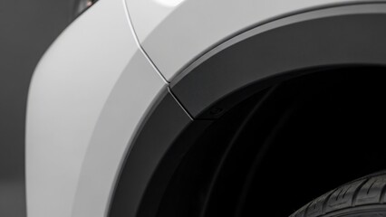 Close-up of a car's front fender and wheel in black and white.