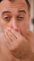 Fototapeta premium Vertical photo Morning fatigue revealed, Yawning man shows tiredness, Closeup of sleepy man revealing exhaustion, Detailed portrait of man in bathroom displaying morning weariness and vulnerability