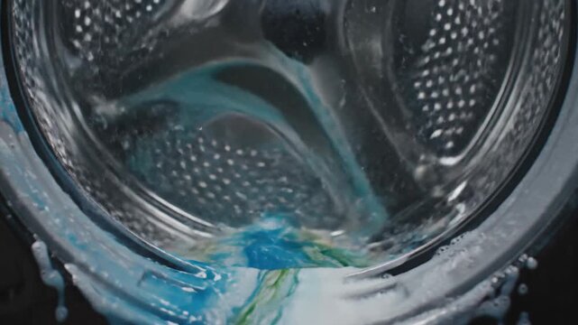 Washing machine drum with detergent pod dissolving in water creating dynamic splashes