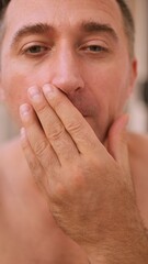 Fototapeta premium Vertical photo Silent individual hides face, Individual gently blocks mouth to prevent germs from spreading, Quiet person carefully conceals their mouth with soft coverings during coughing in restroom