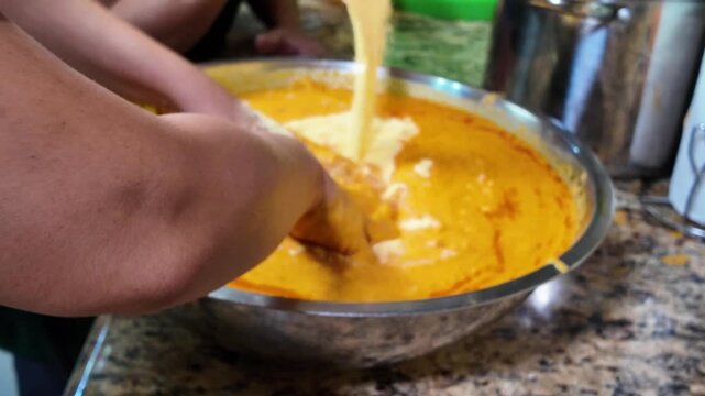 Close up manual kneading of corn dough with onoto to make hallacas Venezuelan Food