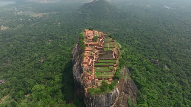 Sri Lanka cinematic drone sweep around Sigiriya Lion Rock, capturing the summit ruins, terraces and dense forest below.