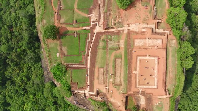 Sri Lanka vertical drone shot revealing Sigiriya Rock Fortress entrance area and jungle canopy below.