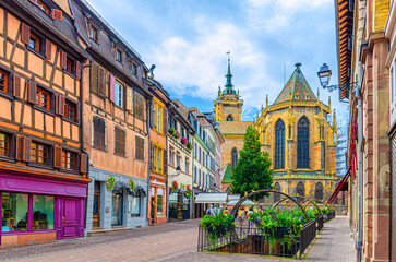 Naklejka premium Old houses half-timbered style colorful facade, medieval buildings shutters windows on Rue de l'Église street, Saint-Martin church in old town Colmar city historic centre, Alsace region, France