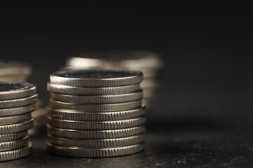 Many stacked coins on gray table against blurred background, closeup. Space for text