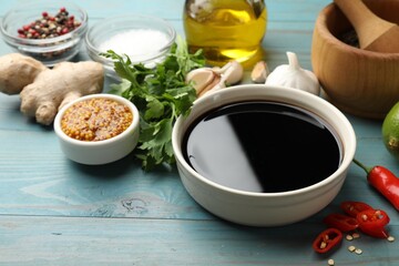 Soy sauce and other different ingredients for marinade on light blue wooden table, closeup
