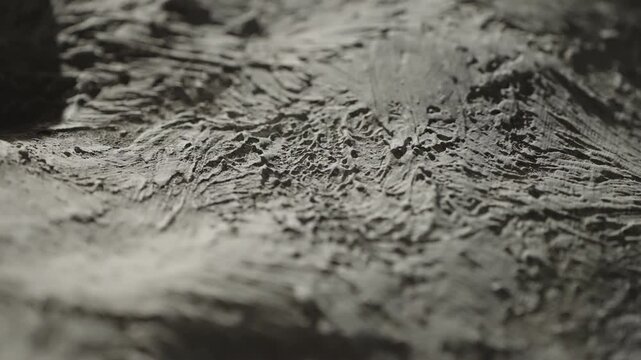 Macro close-up of rough gray plaster surface with heavy trowel marks and ridges, highlighting tactile texture, sculpted grooves, and subtle shadows in abstract composition