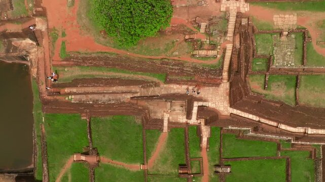 Sri Lanka aerial top view over Sigiriya summit complex, focusing on the rectangular reservoir and surrounding brick structures and staircases.