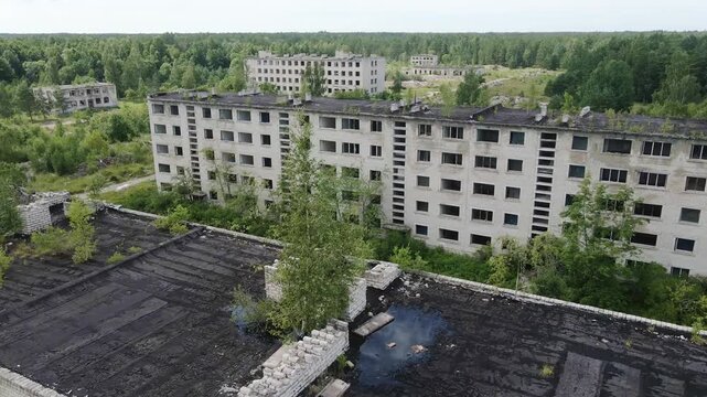 Aerial movement reveals forgotten military base surrounded by dense forest