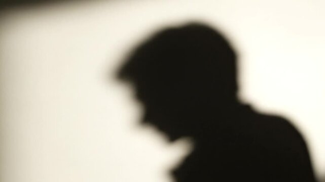 Silhouette of a person's head casting a shadow on a wall in a sequence of frames