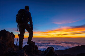 Fototapeta premium Adventurer Silhouette Standing on Mountain Ridge at Sunrise Over Clouds