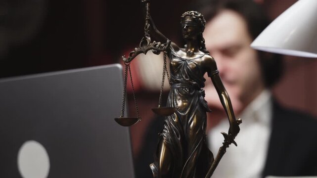 Businessman lawyer or attorney taking notes and studying a case while sitting at a laptop in a modern office. Concept law, legal work, professional environment