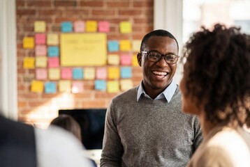 Happy black businessman with glasses laughing with a colleague in a modern creative office setting