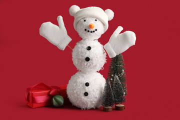 Fototapeta premium Funny snowman with Christmas trees and gift on red background