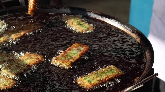 Deep-frying Thai chive cakes on a street food stall