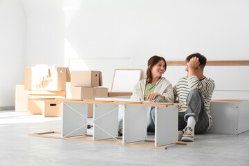 Young couple assembling shelving unit in bedroom on moving day