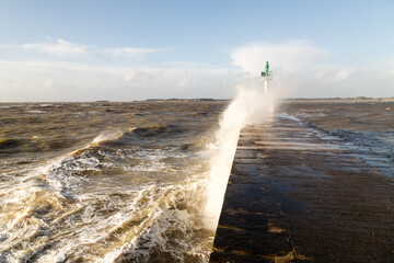 Jetée avec phare vert dans la tempête sous un ciel bleu. Pointe de Merquel, Mesquer © YVO-Photos