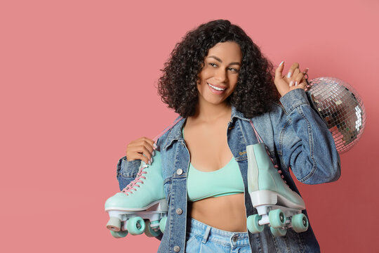 Happy woman with disco ball and roller skates on pink background