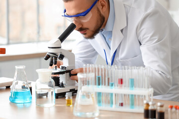 Fototapeta premium Male scientist looking through microscope in laboratory