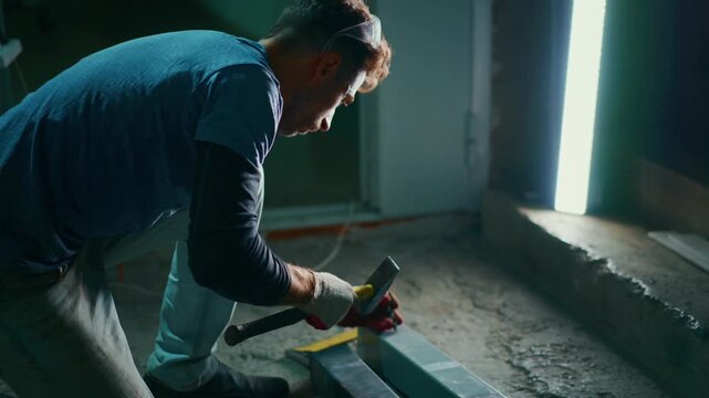 focused craftsman smoothing tile edge with tool near bright entranceway, detailed view of skilled worker carefully polishing tile border with hand tool beside illuminated doorway