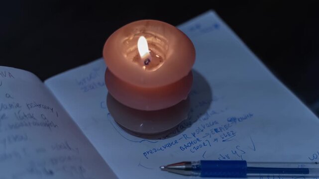 A burning candle on a child's school notebook. Ukraine: Surviving blackout and cold during the war.