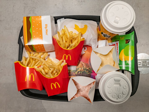 WARSAW, POLAND - JANUARY 8, 2026: A top-down view of a McDonald's fast food tray filled with a Big Mac, three servings of french fries, McFlurry desserts, an apple pie, and a drink on a grey surface